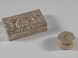 une petite boîte en argent et une pièce de monnaie posées sur une table