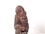 une petite statue représentant un singe assis sur une surface blanche