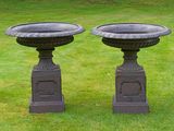 two black urns sitting in the middle of a grassy field