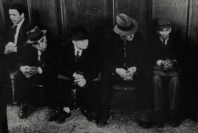 photographie en noir et blanc d'un groupe d'hommes assis les uns à côté des autres