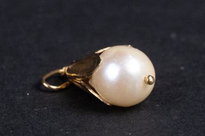 pendentif en perle sur un fond noir, avec un fermoir plaqué or