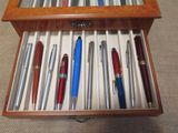 many pens in a wooden box on the floor