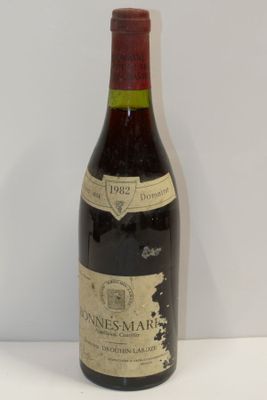 une vieille bouteille de vin posée sur une table blanche