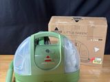 une photo d'un aspirateur vert posé sur une table en bois