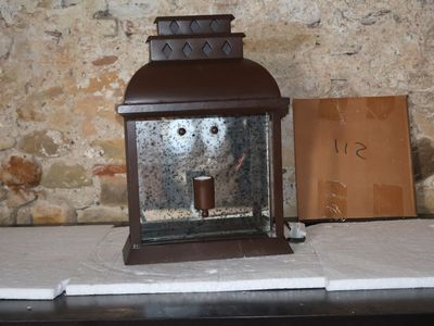 une petite lanterne posée sur une table à côté d'un panneau
