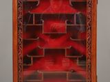 une vieille vitrine en bois avec une porte en verre rouge