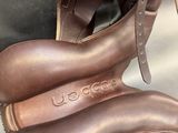 pair of brown leather shoes sitting on top of a brown bag