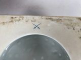 a white toilet with a blue cross mark on it