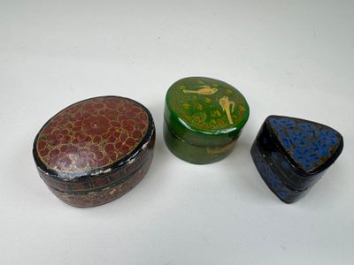 Trois petites boîtes sont posées sur une table devant un fond blanc.