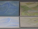 four paintings of mountains are displayed on a table