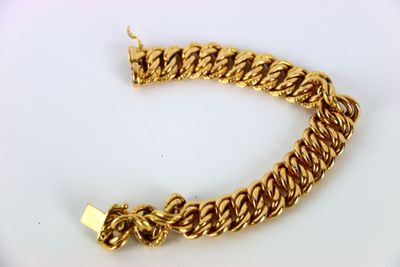 gros plan d'un bracelet en chaîne en or sur une surface blanche