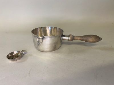 une tasse en argent avec une cuillère et un repose-cuillère posés sur une table