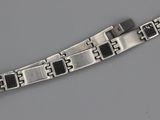 une image représentant un bracelet en argent orné de carrés noirs