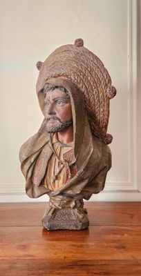 statue d'un homme coiffé d'un chapeau, assis sur un plancher en bois