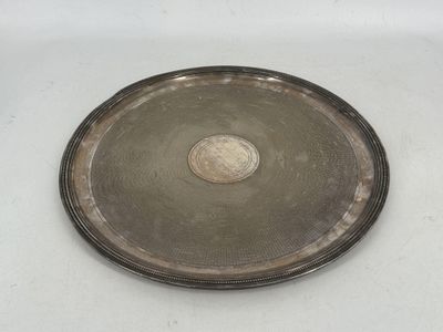 une vieille assiette en argent sur laquelle repose une pièce de monnaie, posée sur un fond blanc