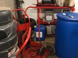 a red cart that is next to a stack of blue barrels