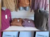une présentation de pulls et de sacs sur une étagère dans un magasin