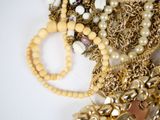a pile of gold and pearl jewelry on a white surface
