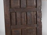 someone is standing next to an old wooden door with a wooden handle