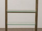 a brass and glass bookcase on a wooden floor