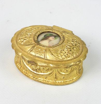 a small gold box with a picture of a woman on it