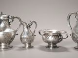 trois théières en argent et deux tasses en argent posées sur une table