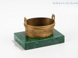a green marble base with a brass bowl on it