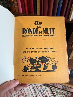 une personne tenant un livre à la main devant une bibliothèque