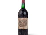 an old bottle of wine sitting on top of a white surface