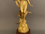 statue en or représentant une femme tenant un oiseau, posée sur un socle en marbre