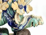 a figurine of a man with a sword and flowers on his head