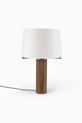 une lampe de table en bois surmontée d'un abat-jour blanc