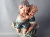 a figurine of a boy and a girl hugging on top of a tree