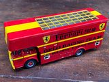 un bus à deux étages rouge et jaune posé sur un plancher en bois