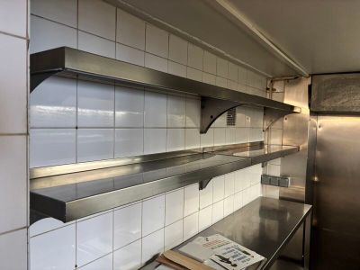 une étagère en acier inoxydable dans une cuisine, sur laquelle est posé un livre