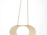 a gold necklace hanging from a gold chain with a circular design