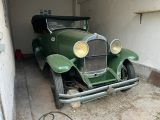 a green car parked in a garage with a man standing next to it