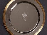 a silver plate with a gold rim and a crown on it