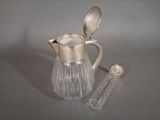 a silver and glass pitcher with a spoon in it