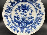 a blue and white plate with flowers and leaves on it