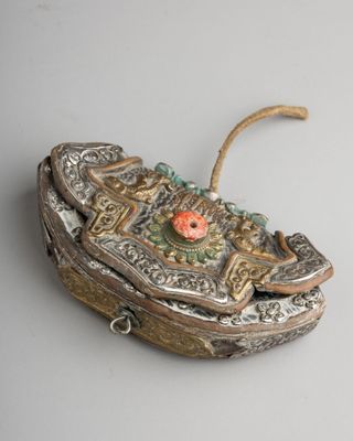 an old silver and gold box with a red flower on it