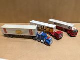 trois camions miniatures et un semi-remorque posés sur une table