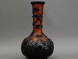 un vase noir et orange posé sur une surface grise