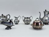 five silver teapots and a silver bowl on a table