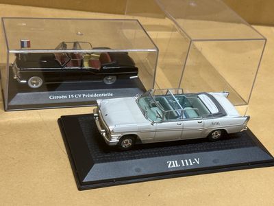 deux modèles réduits de voitures exposés dans une vitrine posée sur une table