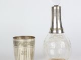 une bouteille en verre et une coupe en argent posées l'une à côté de l'autre