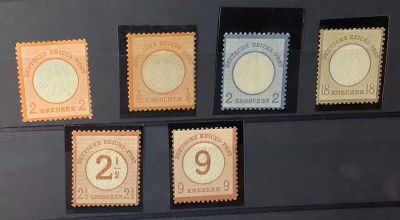 cinq timbres différents présentés dans une vitrine, dont plusieurs exemplaires