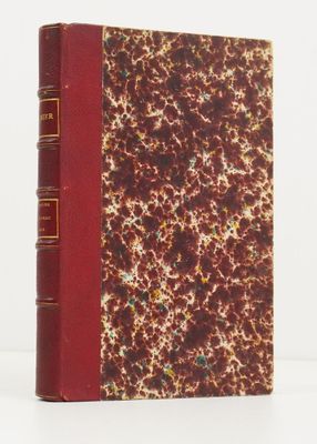 un vieux livre à la couverture rouge posé sur une surface blanche