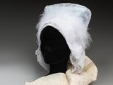une image représentant un chapeau blanc orné de plumes, posé sur la tête d'un mannequin