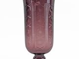 purple glass vase sitting on top of a wooden stand